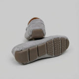 Par do modelo Mocassim Driver de Camurça Capri Dune, na cor cinza, com um dos solados voltado para a câmera.