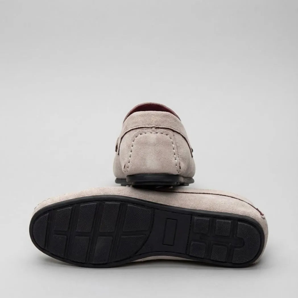 Par do modelo Mocassim Driver de Camurça Capri Tobacco, na cor branco, com um dos solados voltado para a câmera.