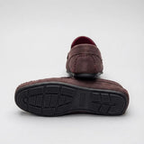 Par do modelo Mocassim Driver de Camurça Capri Tobacco, na cor marrom-escuro, com um dos solados voltado para a câmera.