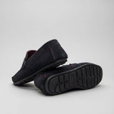 Par do modelo Mocassim Driver de Camurça Capri Tobacco, na cor escuro, com um dos solados voltado para a câmera.