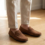Mocassim Driver de Camurça Capri Tobacco na cor marrom, usado com calça clara de barra dobrada.