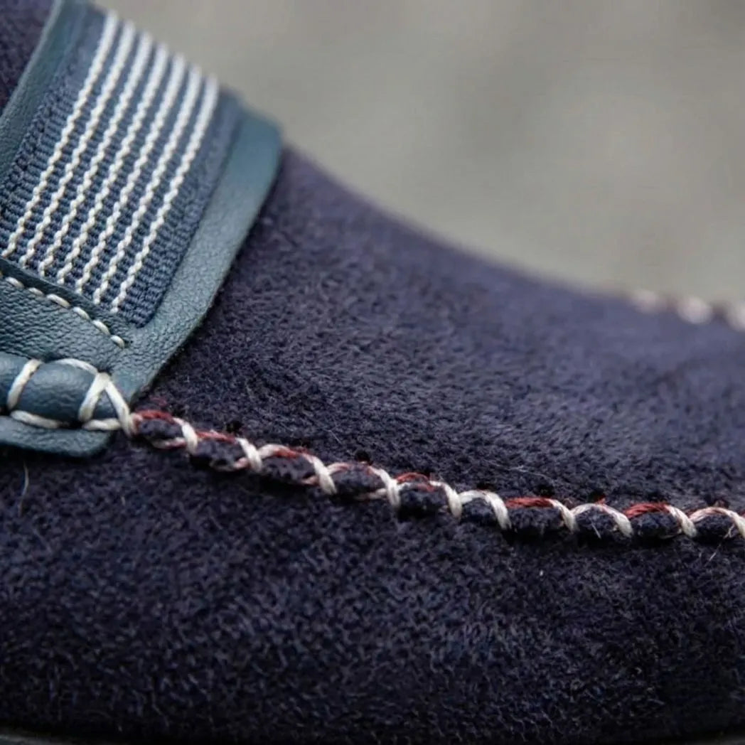 Mocassim Driver de Camurça Havana: detalhe da textura azul-escura, da faixa frontal listrada e da costura clara cruzada.