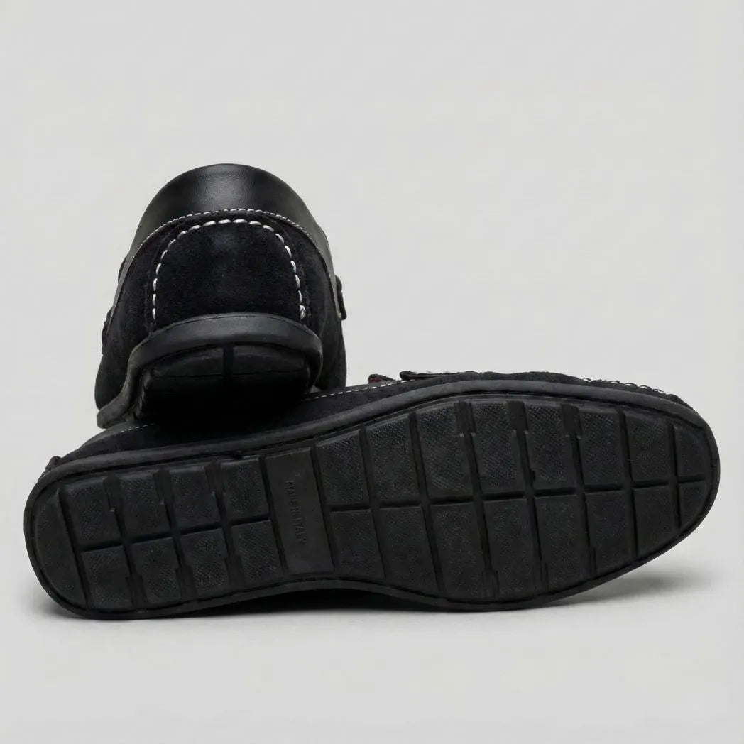 Mocassim Driver de Camurça Stripes: par preto com um sapato virado, mostrando a sola preta com sulcos.