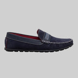 Mocassim Driver de Camurça Stripes: modelo azul-escuro de perfil, com faixa frontal listrada e costura clara cruzada.