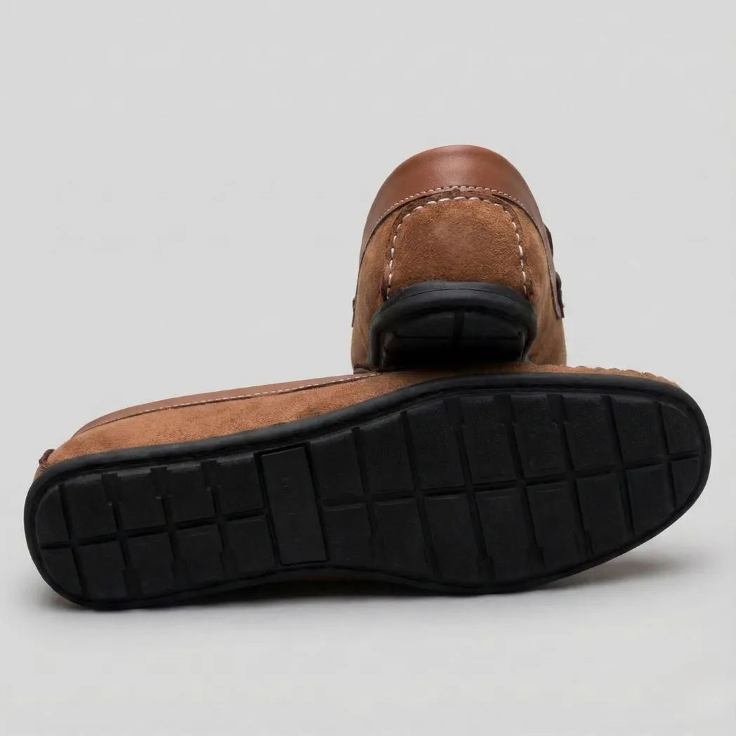 Mocassim Driver de Camurça Stripes: par marrom com um sapato virado, mostrando a sola preta com sulcos.