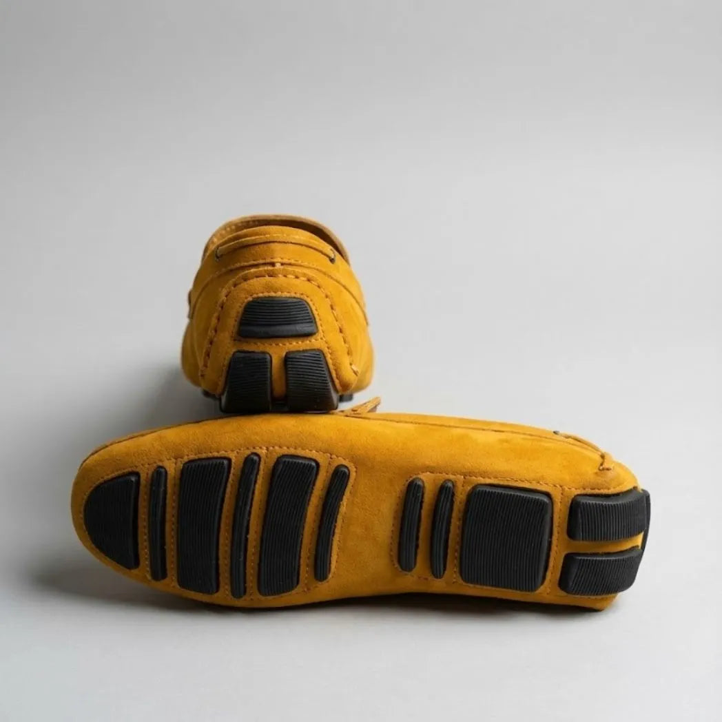 Par do modelo Mocassim Driver de Couro Capri Nero, na cor amarelo, com um dos solados voltado para a câmera.