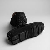 Par do modelo Mocassim Driver de Couro Capri Nero, na cor preto, com um dos solados voltado para a câmera.