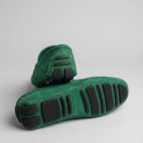 Par do modelo Mocassim Driver de Couro Capri Nero, na cor verde, com um dos solados voltado para a câmera.