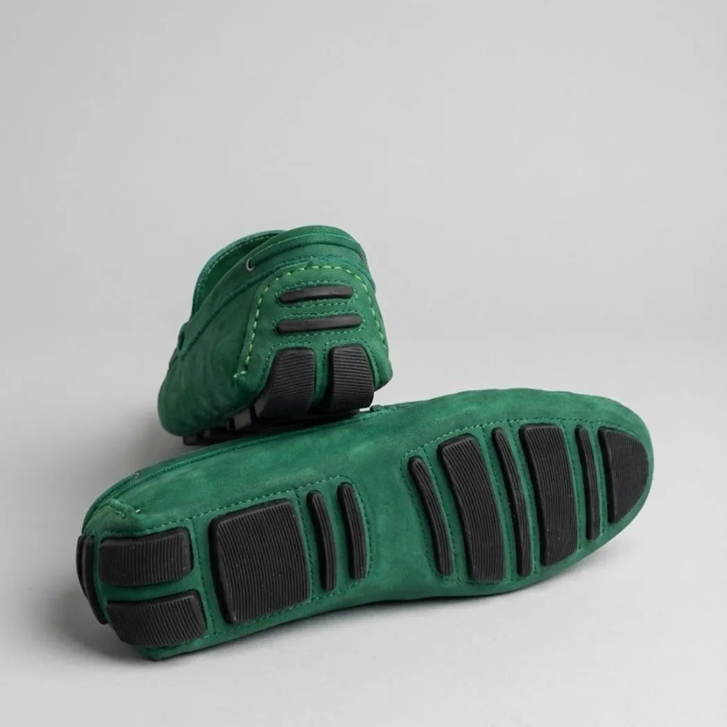 Par do modelo Mocassim Driver de Couro Capri Nero, na cor verde, com um dos solados voltado para a câmera.