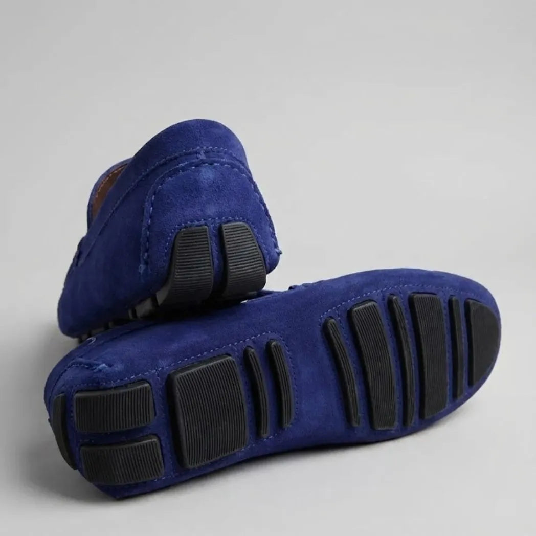 Par do modelo Mocassim Driver de Couro Capri Nero, na cor azul, com um dos solados voltado para a câmera.