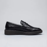 Mocassim Loafer Londres de Couro: modelo preto de perfil, com faixa frontal e sola preta de borda estriada.
