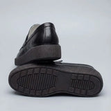 Mocassim Loafer Londres de Couro: par preto com um sapato virado, mostrando a sola preta com sulcos.
