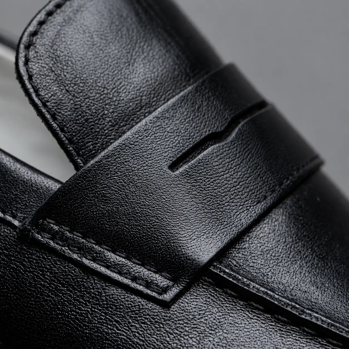Detalhe do couro preto e da faixa penny lisa do Mocassim Loafer Londres All Black.