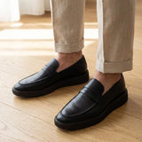 Mocassim Loafer Londres de Couro: par preto com sola preta usado com calça clara dobrada na barra.