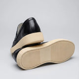 Mocassim Loafer Londres de Couro: par preto com um sapato virado, mostrando a sola bege.