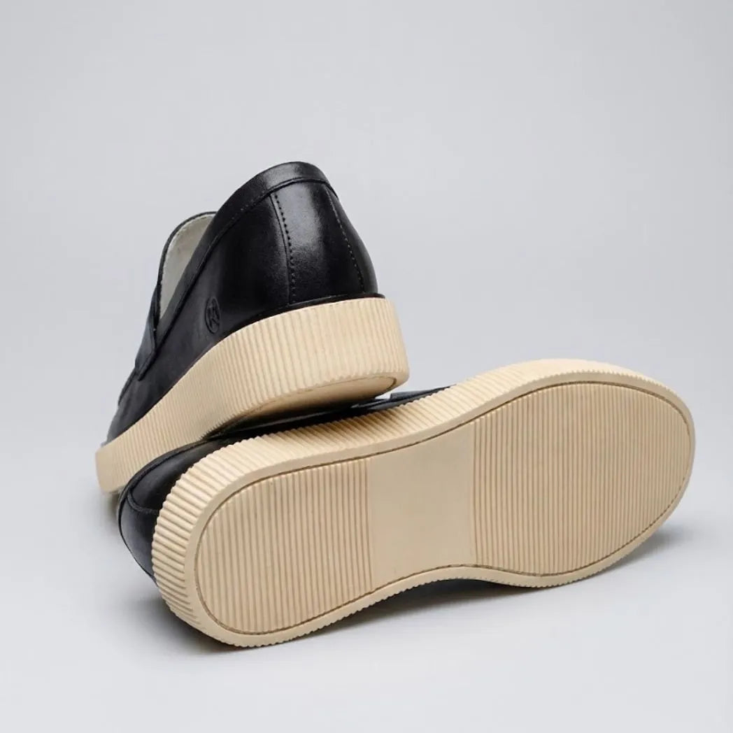 Mocassim Loafer Londres de Couro: par preto com um sapato virado, mostrando a sola bege.
