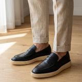 Mocassim Loafer Urban Londres de Couro: par preto com sola bege usado com calça clara dobrada na barra.