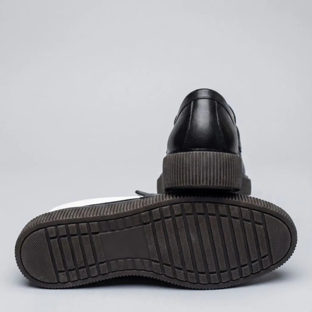Mocassim Loafer Urban Londres de Couro: par preto com um sapato virado, mostrando a sola preta com sulcos.