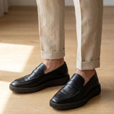 Mocassim Loafer Urban Londres de Couro: par preto com sola preta usado com calça clara dobrada na barra.