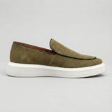 Mocassim Loafer de Camurça Vanguard: modelo verde-oliva de perfil, com contorno escuro da parte frontal e sola branca.