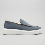 Mocassim Loafer de Camurça Vanguard: modelo cinza de perfil, com sola branca.