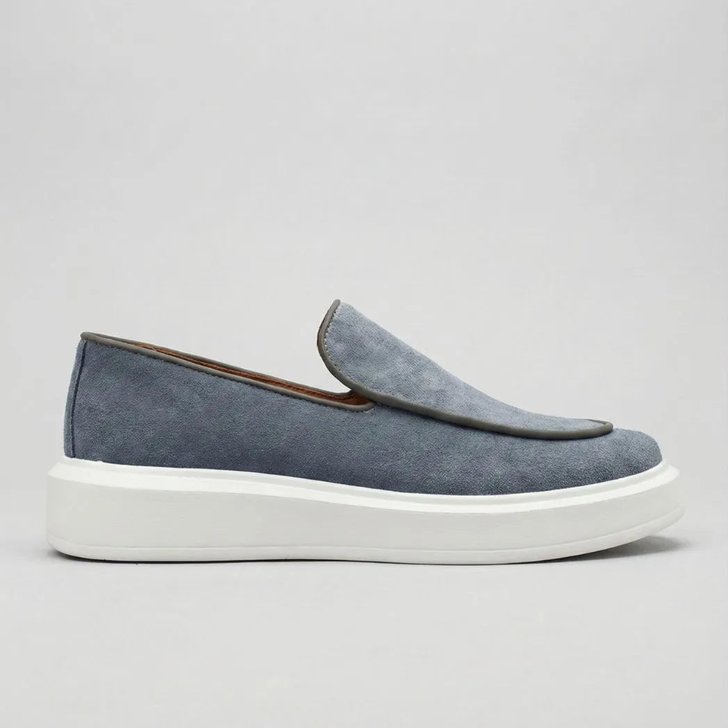 Mocassim Loafer de Camurça Vanguard: modelo cinza de perfil, com sola branca.
