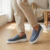 Mocassim Loafer de Camurça Vanguard: par cinza com sola branca usado com calça clara dobrada na barra.
