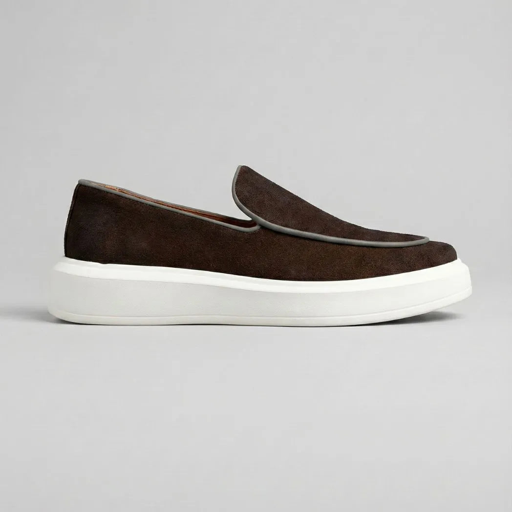 Mocassim Loafer de Camurça Vanguard: modelo marrom-escuro de perfil, com contorno da parte frontal claro e sola branca.