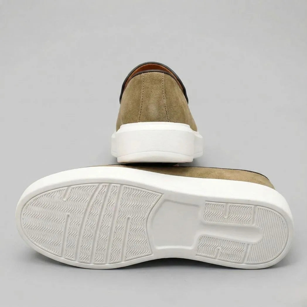 Mocassim Loafer de Camurça Vanguard: par verde-oliva com um sapato virado, mostrando a sola branca.