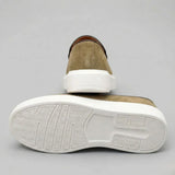 Mocassim Loafer de Camurça Vanguard: par verde-oliva com um sapato virado, mostrando a sola branca.