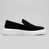 Mocassim Loafer de Camurça Vanguard: modelo preto de perfil, com sola branca.