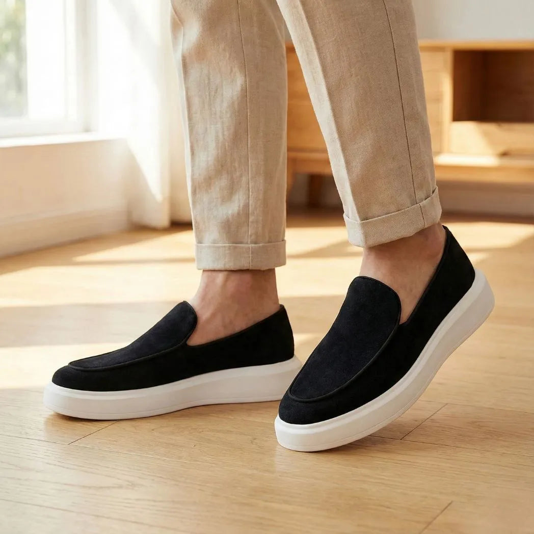 Mocassim Loafer de Camurça Vanguard: par preto com sola branca usado com calça clara dobrada na barra.