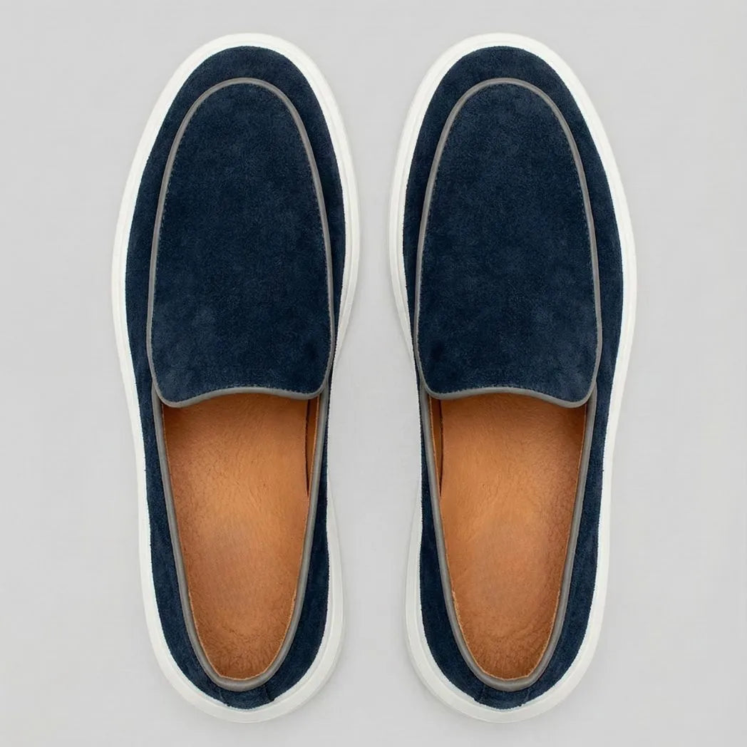 Mocassim Loafer de Camurça Vanguard: par azul-escuro visto de cima, mostrando o contorno claro da parte frontal e o interior marrom.