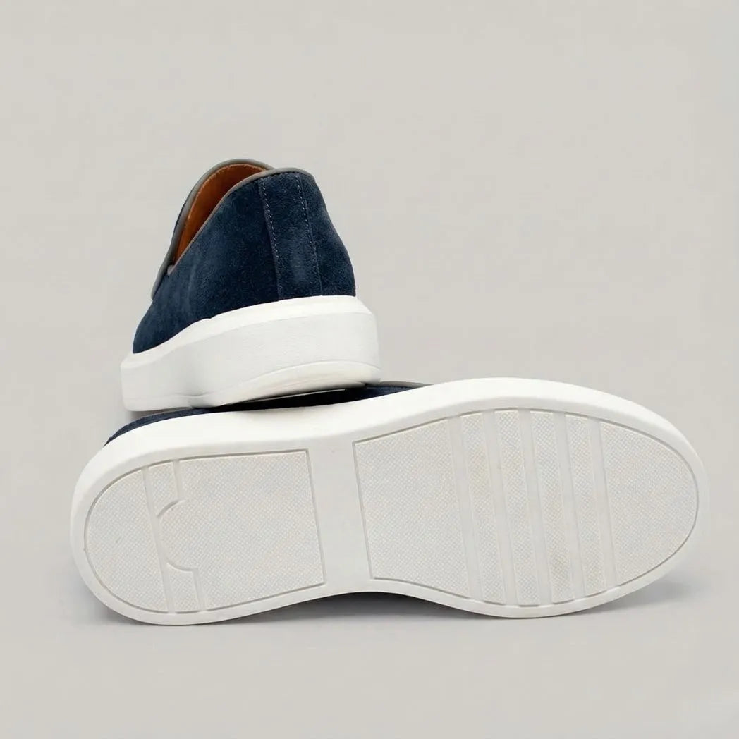 Mocassim Loafer de Camurça Vanguard: par azul-escuro com um sapato virado, mostrando a sola branca.
