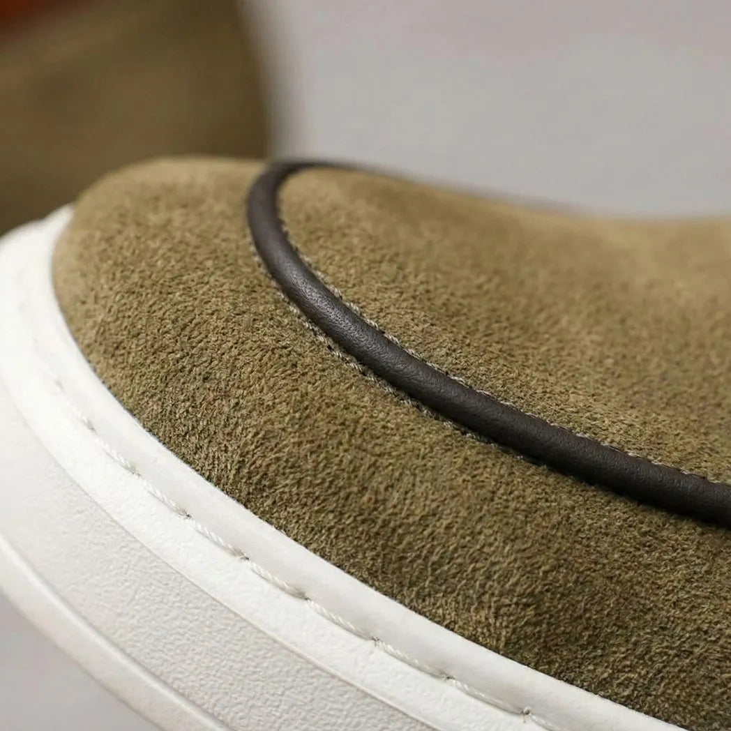 Mocassim Loafer de Camurça Vanguard: detalhe da textura verde-oliva, do contorno escuro e da borda da sola branca.