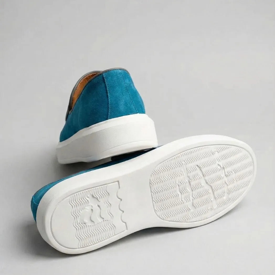 Mocassim Loafer de Camurça Vanguard: par azul com um sapato virado, mostrando a sola branca com relevo.