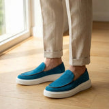 Mocassim Loafer de Camurça Vanguard: par azul com sola branca usado com calça clara dobrada na barra.