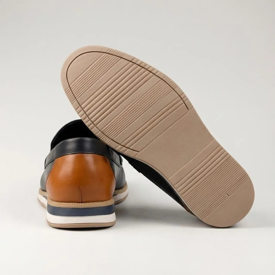 Mocassim Loafer de Couro Contrast: par preto com um sapato virado, mostrando a sola bege e o detalhe marrom na parte traseira.