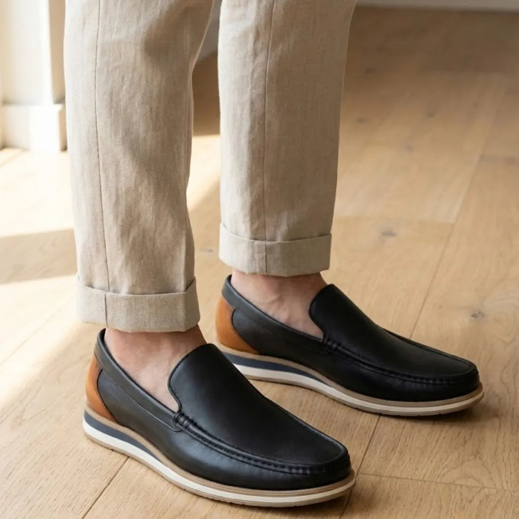 Mocassim Loafer de Couro Contrast: par preto com detalhe marrom na parte traseira e sola bege usado com calça clara dobrada na barra.