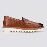 Mocassim Loafer de Couro Napoli: modelo marrom de perfil, com faixa frontal e sola branca de sulcos profundos.