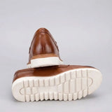 Mocassim Loafer de Couro Napoli: par marrom com um sapato virado, mostrando a sola branca com sulcos profundos.