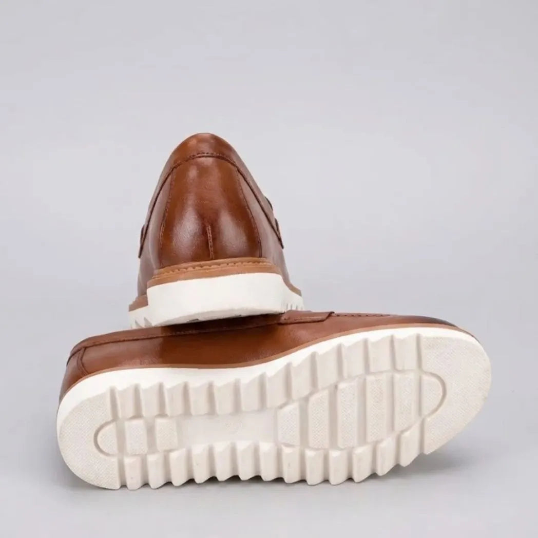 Mocassim Loafer de Couro Napoli: par marrom com um sapato virado, mostrando a sola branca com sulcos profundos.