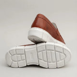 Par do modelo Mocassim Lunar Tratorado, na cor marrom, com um dos solados voltado para a câmera.