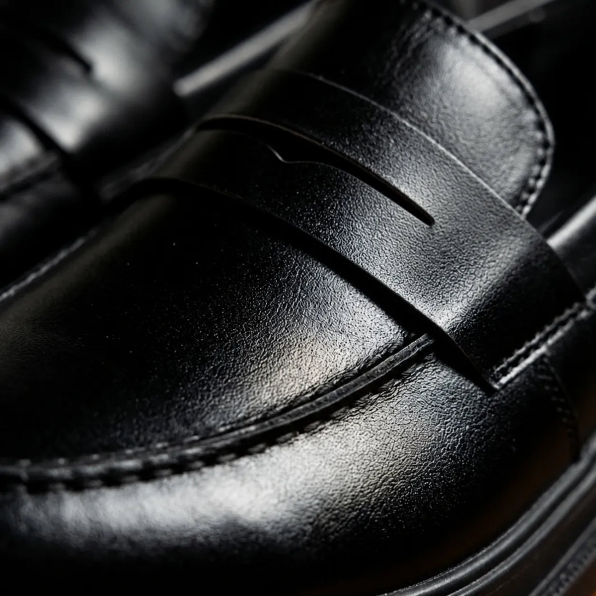 Detalhe da faixa penny sem fivela e das costuras do Mocassim Masculino Piettro Preto em couro.
