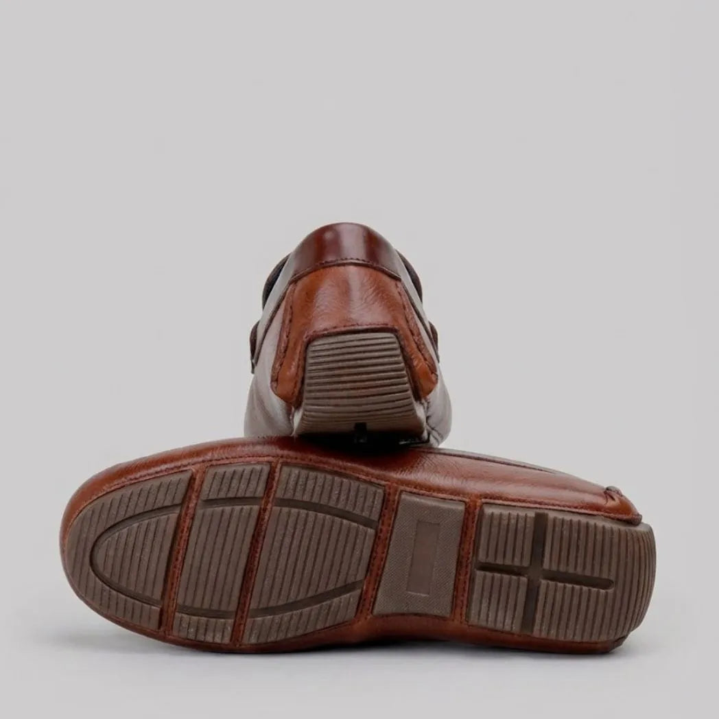Mocassim Masculino Driver de Couro: par marrom com um sapato virado, mostrando a sola marrom com sulcos.