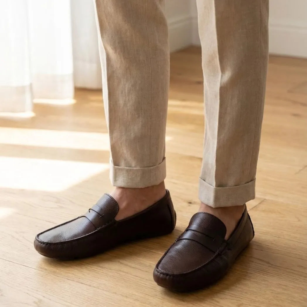 Mocassim Masculino Driver de Couro: par marrom-escuro usado com calça clara dobrada na barra.