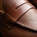 Mocassim Masculino Genova Loafer Couro: detalhe da textura marrom, da faixa frontal e da costura.