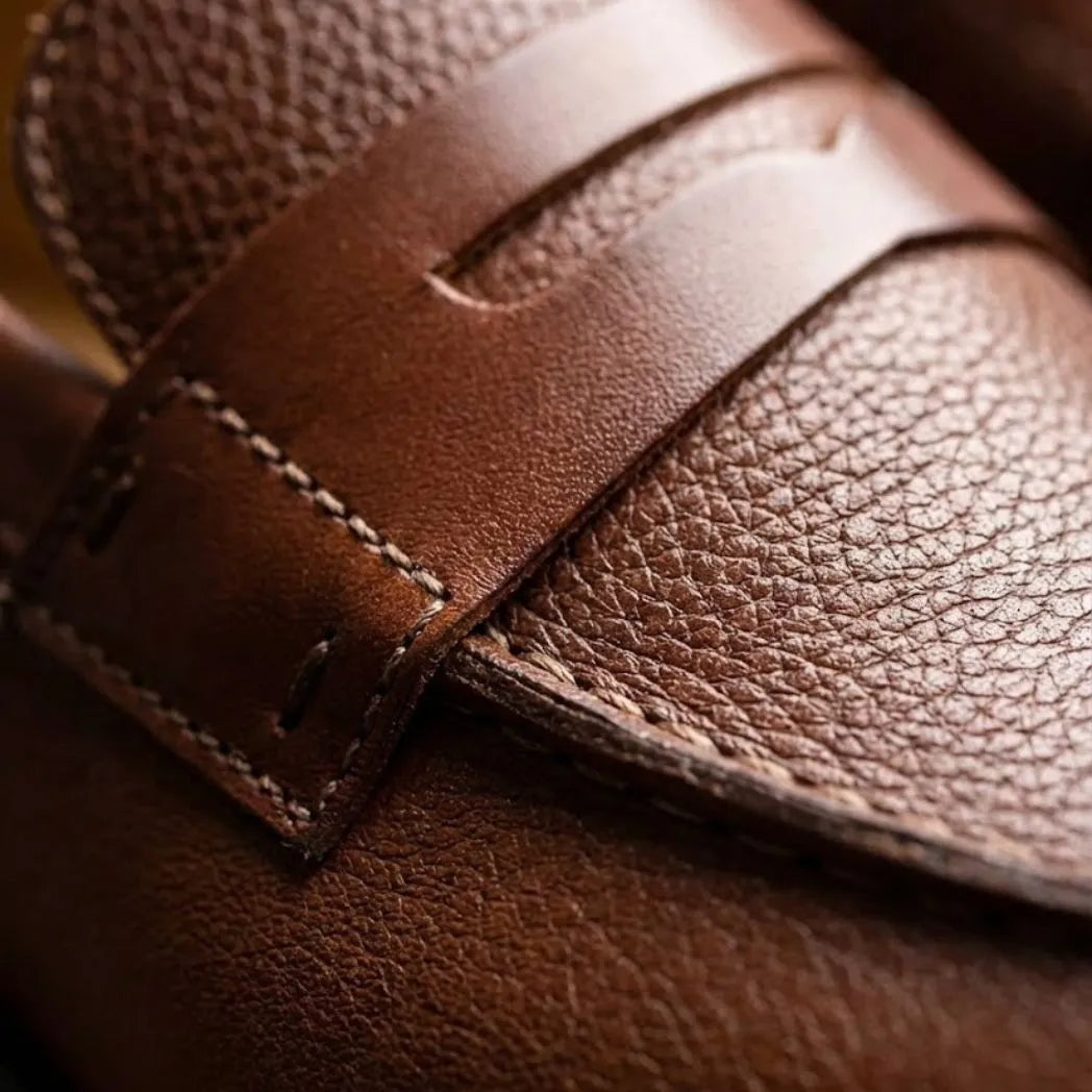 Mocassim Masculino Genova Loafer Couro: detalhe da textura marrom, da faixa frontal e da costura.
