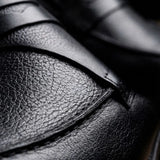 Mocassim Masculino Genova Loafer Couro: detalhe da textura preta, da faixa frontal e da costura.