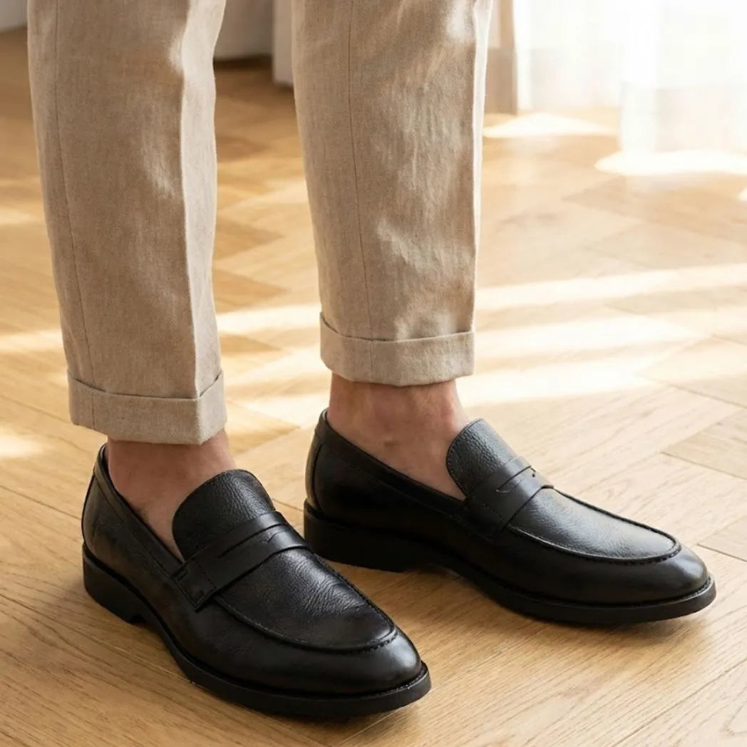 Mocassim Masculino Genova Loafer Couro: par preto usado com calça bege dobrada na barra.